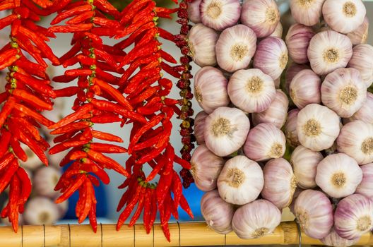 Close-up of several strings of chilli peppers and garlic hanging in a market