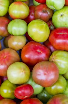 A pattern of colors and rounded shapes formed by a close-up of tomatoes in a market.
