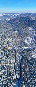 Winding road through frozen forest, mountain pass road in winter