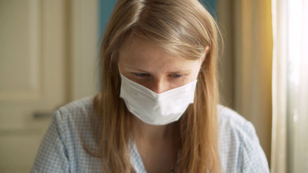 Close up portrait of a handsome woman working from home. Lady in a protective mask looking on a screen of computer. Distant job on quarantine. COVID-19 pandemic