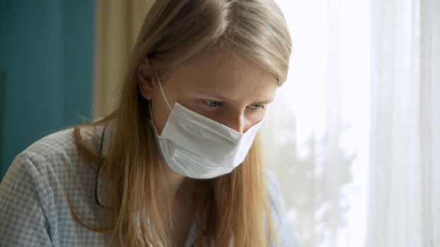 Close up portrait of a handsome woman working from home. Lady in a protective mask looking on a screen of computer. Distant job on quarantine. COVID-19 pandemic