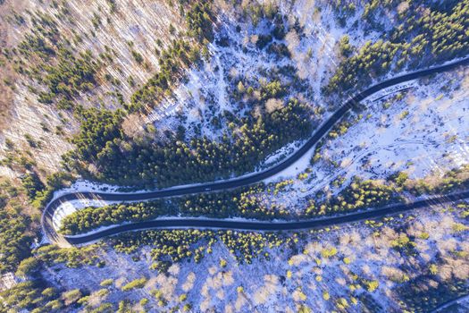 Above view of winding road in forest, winter sunny day