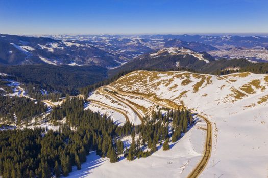 Winter curvy road in Rarau mountains, aerial scene in Romanian Carpathians.