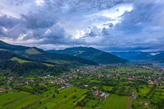 Aerial landscape of mountain valley village in Romanian Carpathians, summer scene