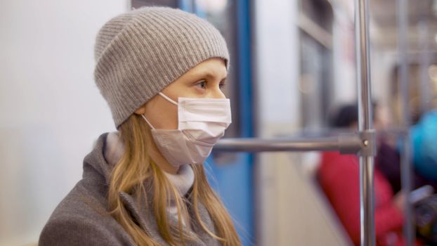 Close up portrait of young woman in protective mask in the subway car. Healthy and safety lifestyle concept. Covid-19 pandemic