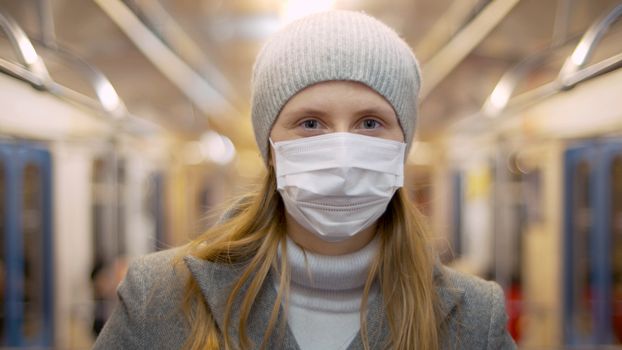 Close up portrait of young woman in protective mask in the subway car. Healthy and safety lifestyle concept. Covid-19 pandemic