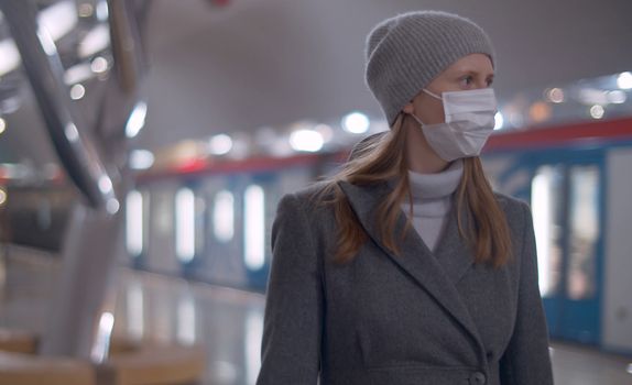 Portrait of young woman in protective mask standing on the subway station. Beautiful blurry background. Healthy and safety lifestyle concept. Covid-19 pandemic