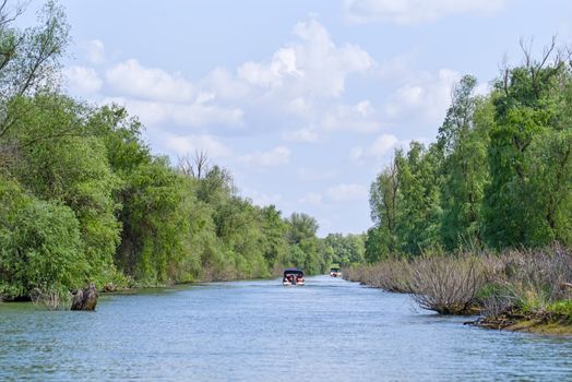 Tourists boats on water canal, Danube Delta landscape in Unesco Heritage