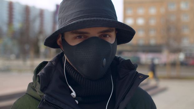 Close up portrait of a young man in a reusable face protective mask outdoors. Coronavirus epidemic in Moscow. Concept of health and safety life. COVID-19 pandemic