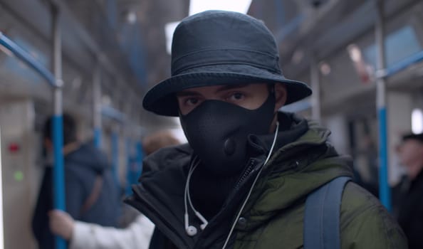 Close up portrait of a young man in a reusable protective mask in subway train. Coronavirus epidemic in big city. Safety life concept. COVID-19 pandemic