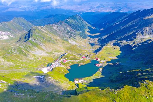 Balea landmark viewed from above: lake, chalets and Transfagarasan road in a summer landscape