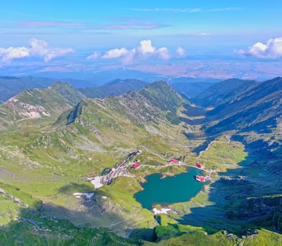Aerial mountain landscape in Fagaras mountains: lake, chalets and Transfagarasan road in a summer landscape