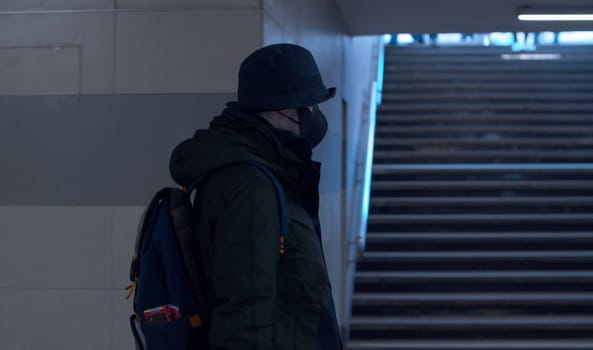 Man in a protective mask walking in the underground crossing. Coronavirus epidemic in the city. Safety life concept. COVID-19 pandemic