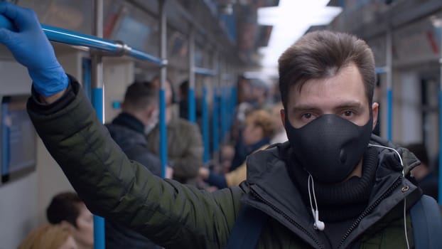 Close up portrait of a young man in a reusable protective mask in subway train. Coronavirus epidemic in big city. Safety life concept. COVID-19 pandemic