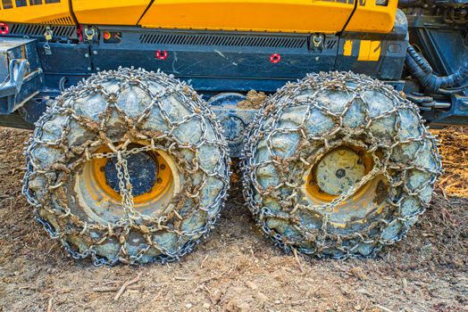 Logging machine wheels equipped with chains working in the forest