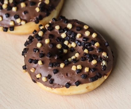 Close up of chocolate brownie donuts on table. The donuts is brown glazed with brownie parts
