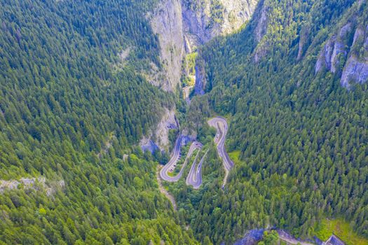 Aerial view of mountain pass, winding road in green forest, Romanian Carpathians.