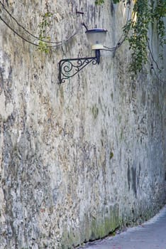 Street lamp on ancient wall in Brasov, Romania, aged fortress brick wall