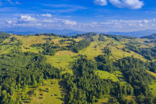 Aerial hill pastures with stacked hay, summer scene.