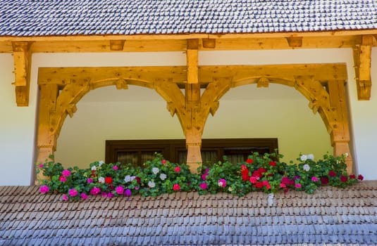 Architecture details at Barsana Monastery in Romania, house balcony with flowers.