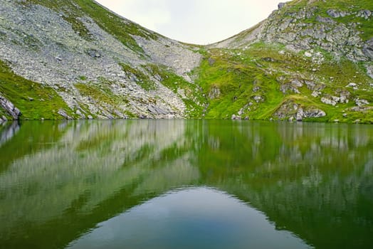 Calm lake reflecting rocky mountain in the summer