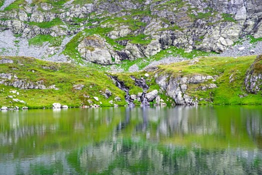 Small brooks feeding rocky mountain lake in a summer landscape