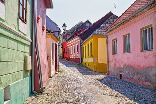 Stone paved road and colorful houses in medieval Sighisoara, Romanian landmark