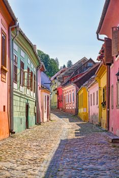 Ancient part of Sighisoara citadel, colorful houses on small paved street. popular tourists destination in Romania