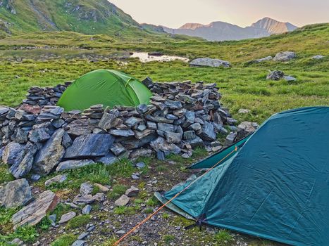 Alpine tents near a pond in Romanian Carpathians, summer mountain landscape