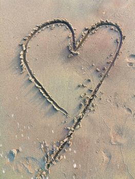 Drawing love symbol in sandy beach