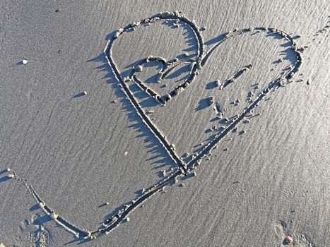 Love hearth on wet sand, sunny beach
