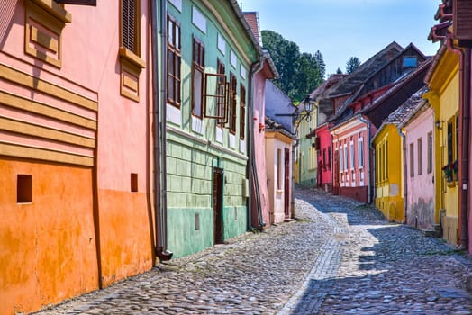 Stone paved street with colorful houses in the medieval city of Sighisoara, Romania