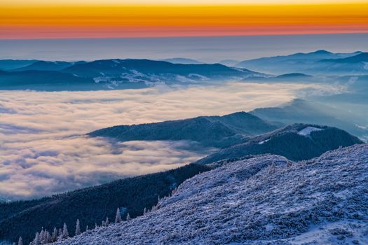 Winter sunrise from mountain top,mist in the valley in Romanian Carpathians.