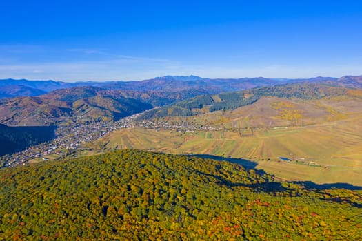 Aerial autumn landscape; forest, fields and rural village, Romanian Carpathians.