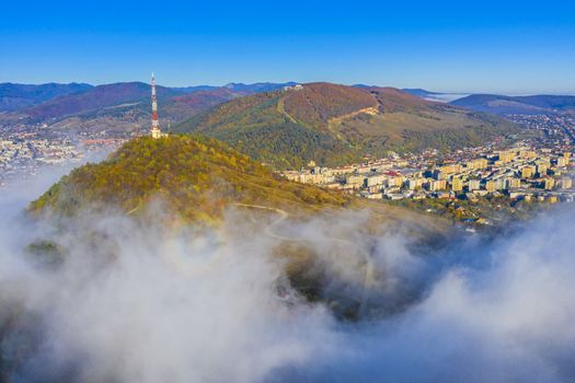 Aerial view of mountain city covered by fog, autumn landscape in Romania
