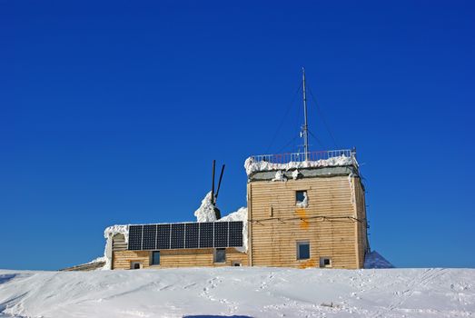 Wooden chalet with solar panels on mountain summit