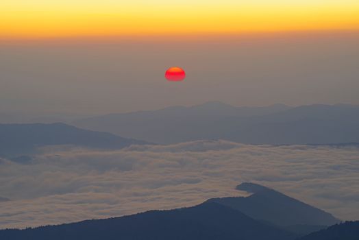 Sunrise scene from mountain top, red sun at horizon