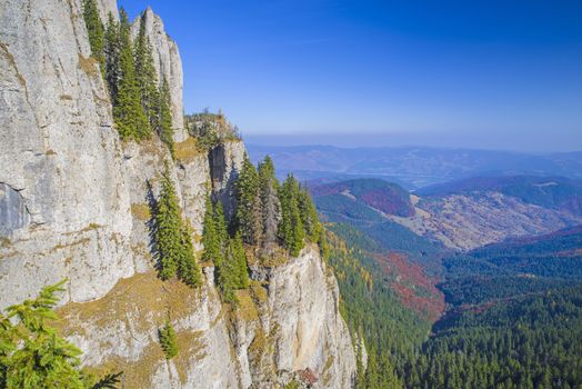 Rock wall in Romanian Carpathians, autumn forest in valley