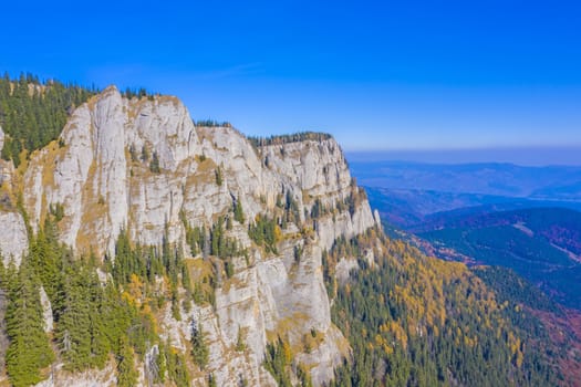 Aerial landscape of autumn mountain wall and forest in Romanian Carpathians.