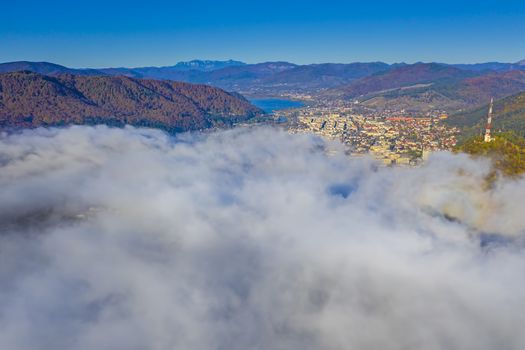Fog clouds comming over mountain city, aerial autumn landscape of Piatra Neamt city in Romania