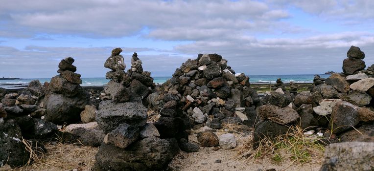 Wish rocks blocks made by people with black stones on the shore of hyeopjae beach in Jeju Island, South Korea.