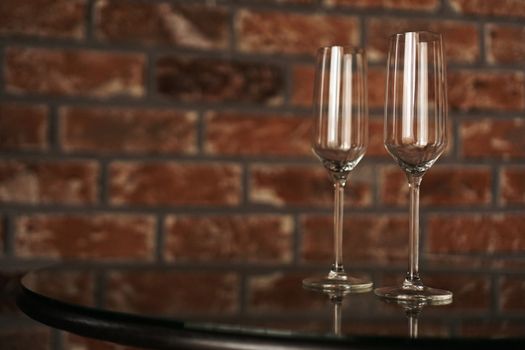 Two glasses on a blurred background of a brick wall. Romantic evening, date. Place for the inscription.