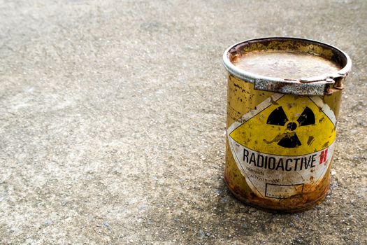 Radiation warning sign on rusty package of radioactive material container on the rough concrete floor