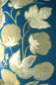 The surface of a blue vase with white flowers decorated with silver ornaments