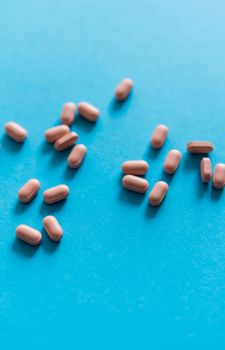 Pink pills on blue background. Medicine, medication, painkillers, tablet, medicaments, drugs, antibiotic, vitamin, treatment. Pharmacy theme. Top view on the pills scattered on the blue surface