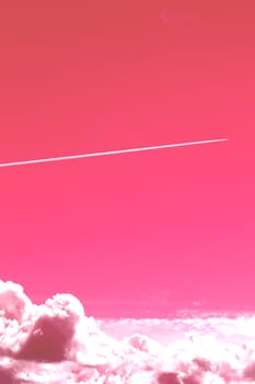 The trail of a flying airplane in a clear pink sky over large clouds.