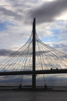 Massive cable-stayed bridge side construction. Clouds in the sky.