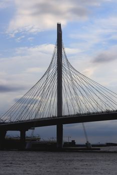 Massive cable-stayed bridge side construction. Clouds in the sky.