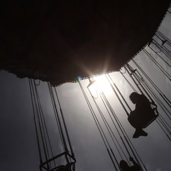 Twisting carousel with children. Silhouettes in counterlight. Amusement park Divo-island. Saint-Petersburg.