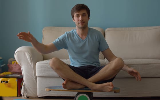 Smiling man sitting on deck for balance. Rocker-roller balance boards. A man holds a balance on the board and pipe.